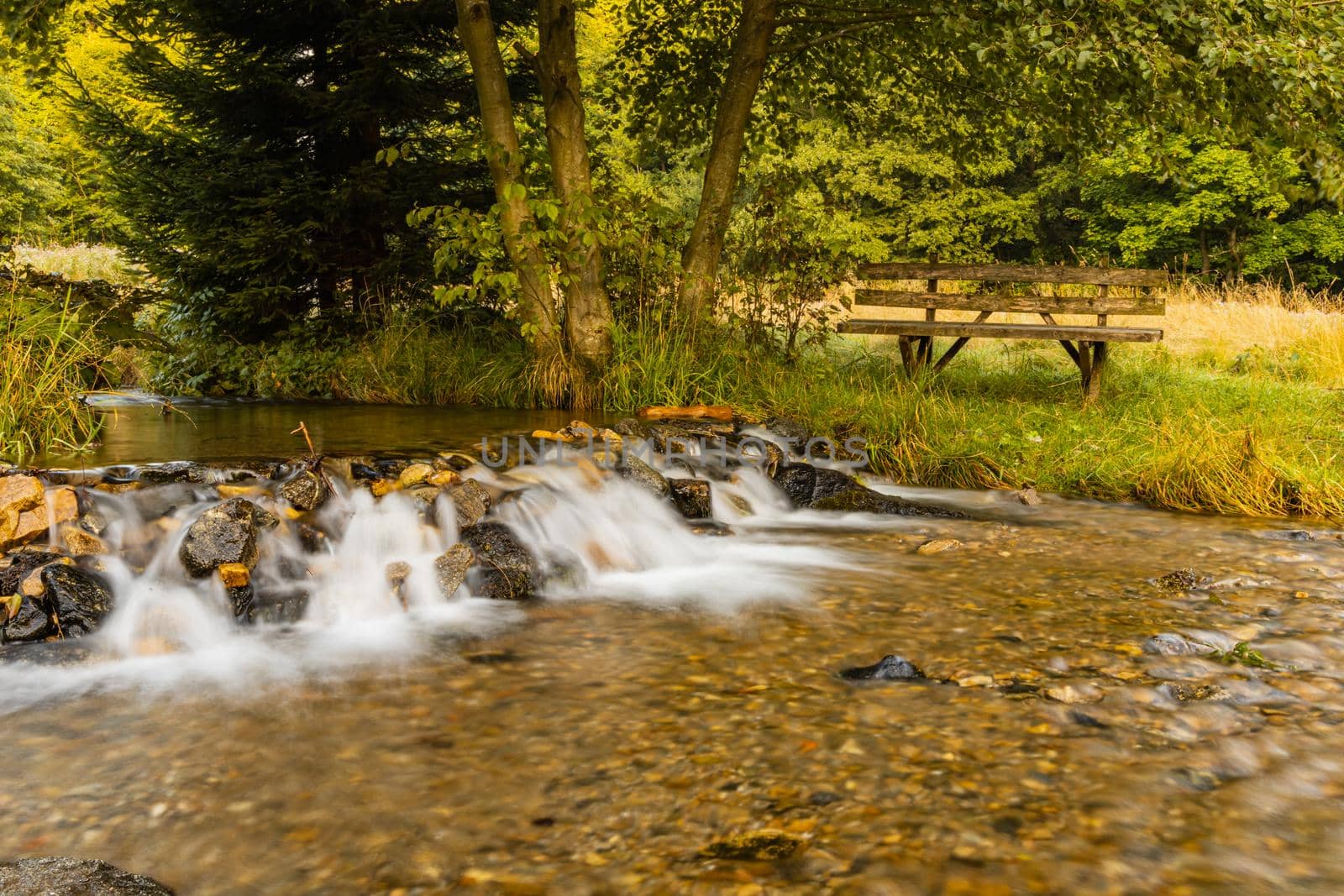 Small beautiful waterfall on Biala Ladecka river in Bielice with wooden bench on the other side by Wierzchu