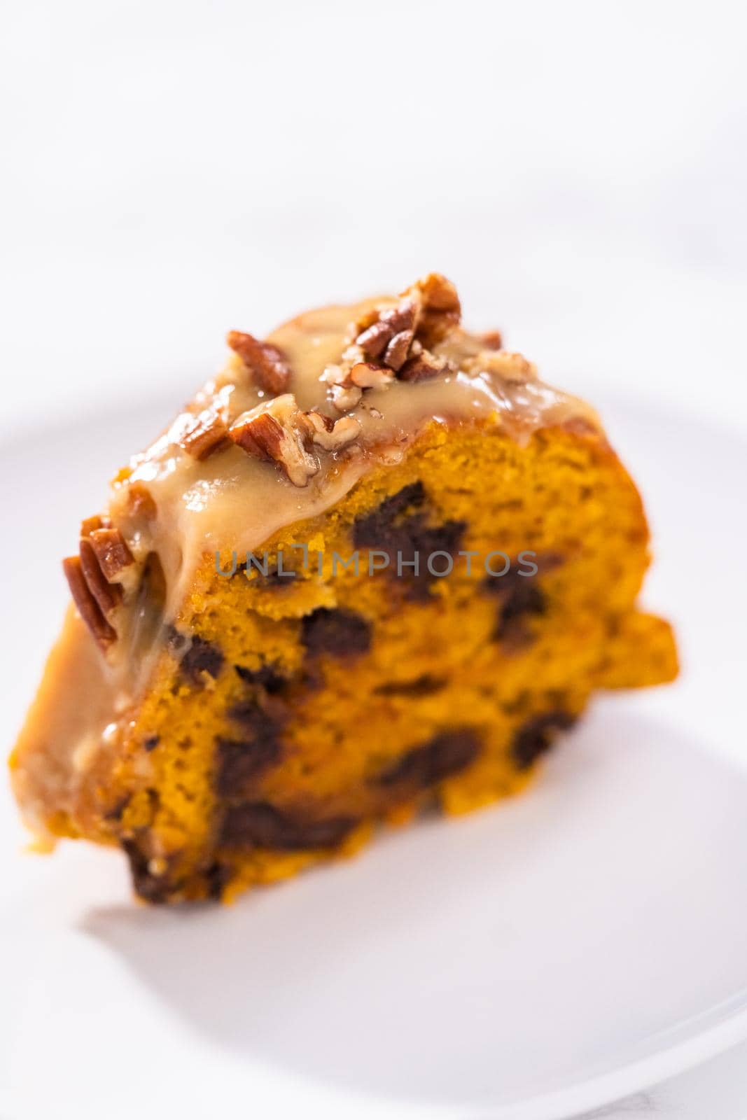 Slice of homemade chocolate pumpkin bundt cake with toffee glaze on a plate.
