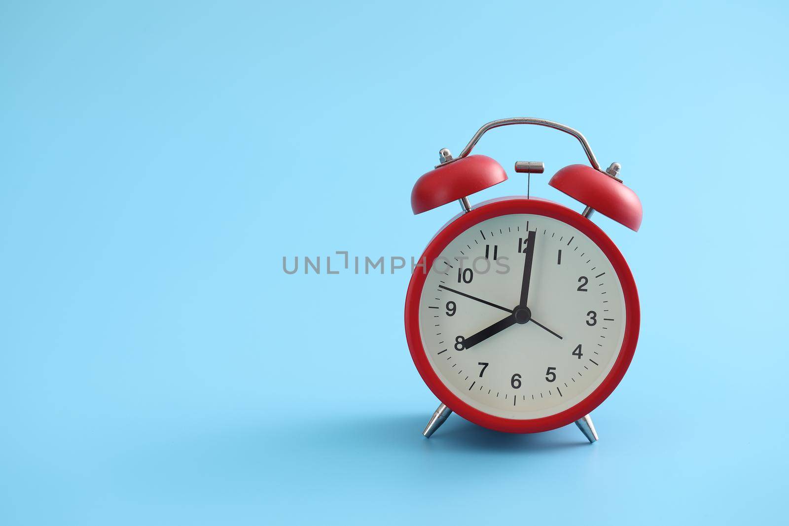 Red retro alarm clock isolated on a blue background by piyato