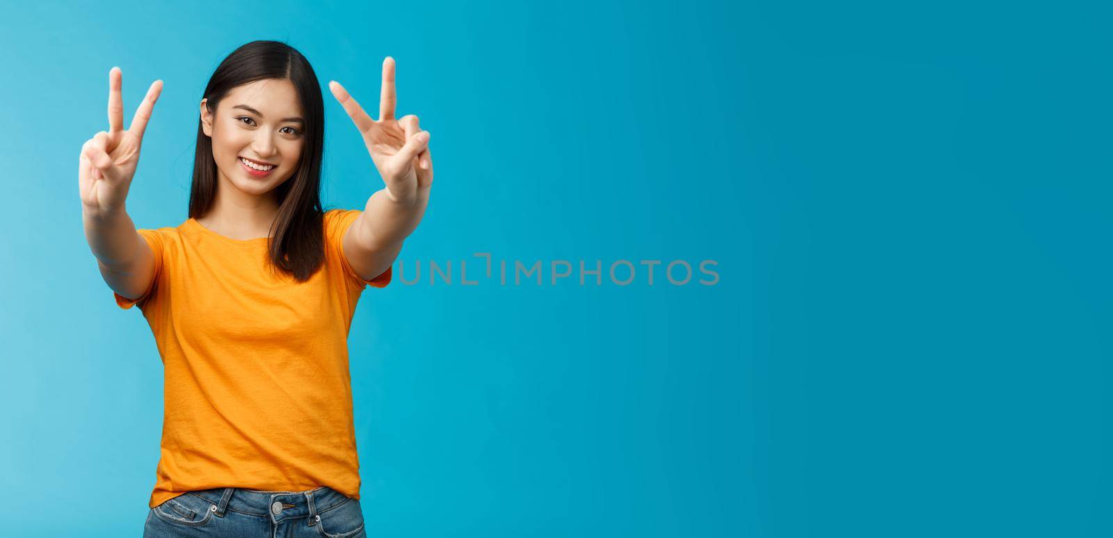 Positive upbeat cute asian girl believe win, aim success extend hands show victory, peace sign smiling broadly, have happy enthusiastic mood, spend carefree vacation travel abroad value pacifism.