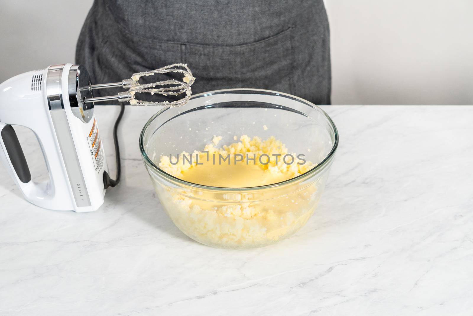 Mixing ingredients in a large glass mixing bowl to bake red velvet bundt cake with cream cheese glaze.