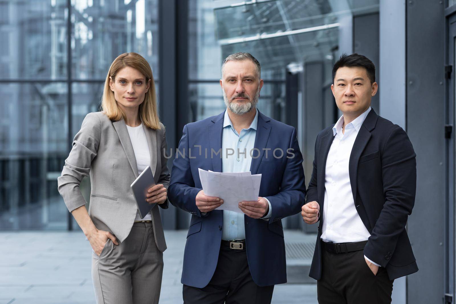 A team of experienced team leaders and specialists, a diverse group of business people, three people in business clothes are serious and focused in business clothes looking at the camera