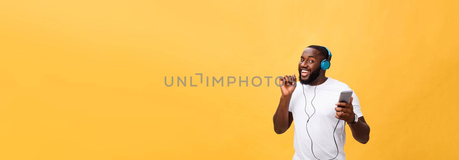 African American man with headphones listen and dance with music. Isolated on yellow background by Benzoix