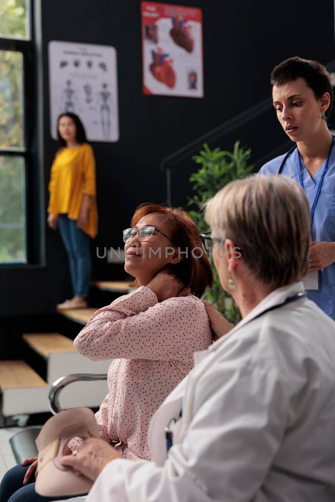 Hospital staff removing cervical neck collar off of injured woman with fracture, dealing with physical pain after injury. Nurse and physician giving support to old patient, rehabilitation therapy.