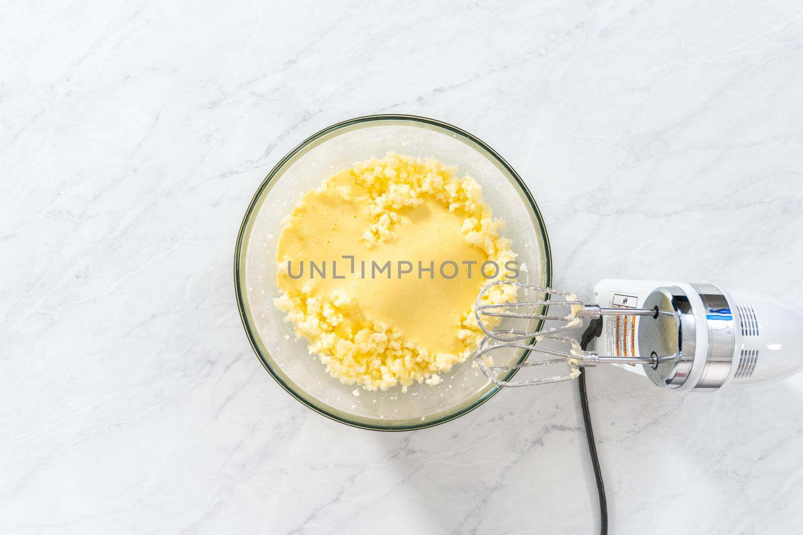 Flat lay. Mixing ingredients in a large glass mixing bowl to bake red velvet bundt cake with cream cheese glaze.