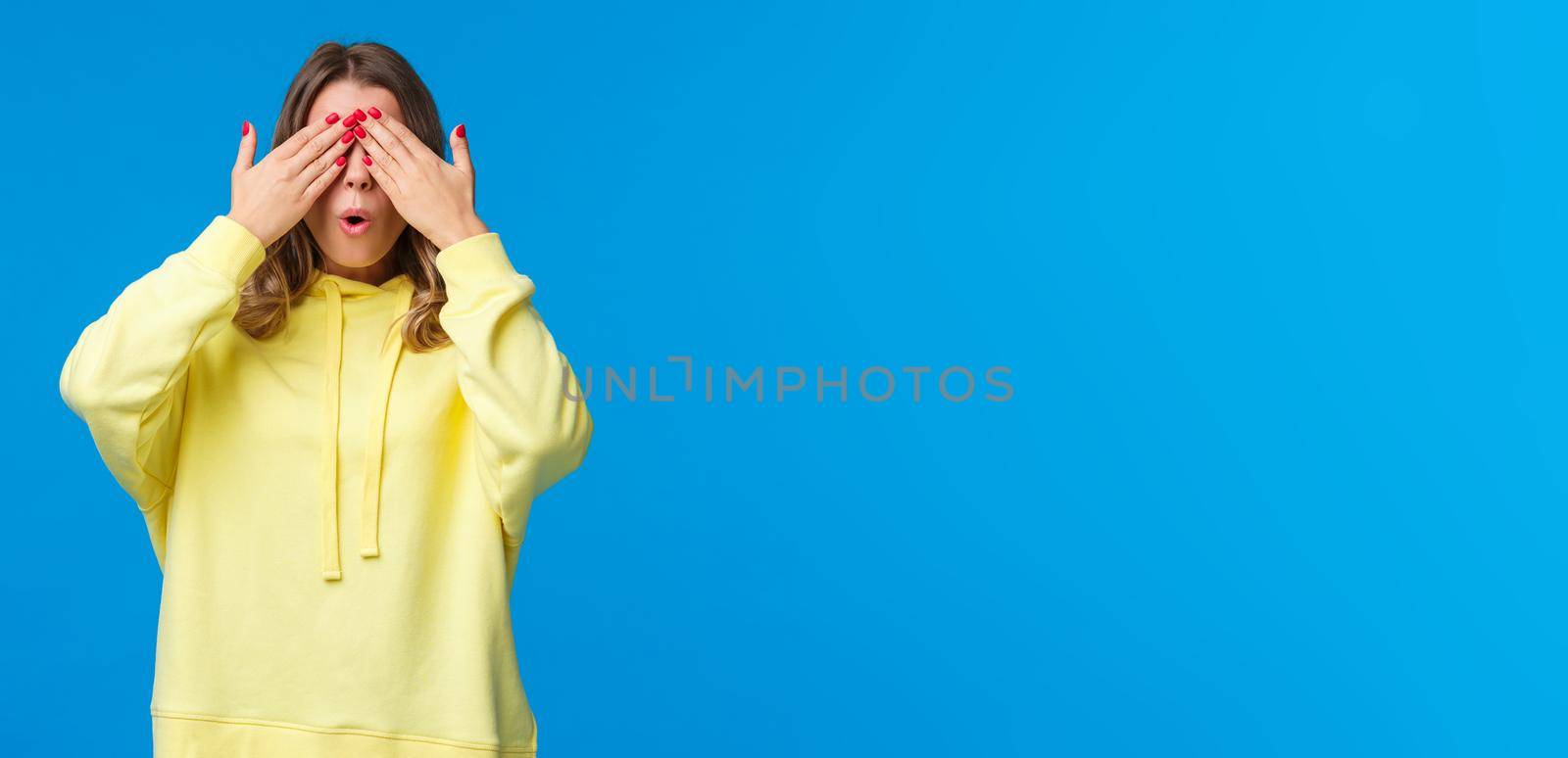 Girl fool around in playful mood, close eyes with hands count to ten, playing hide n seek or peekaboo, waiting for surprise gift, express curiosity and interest, stand blue background awaiting by Benzoix