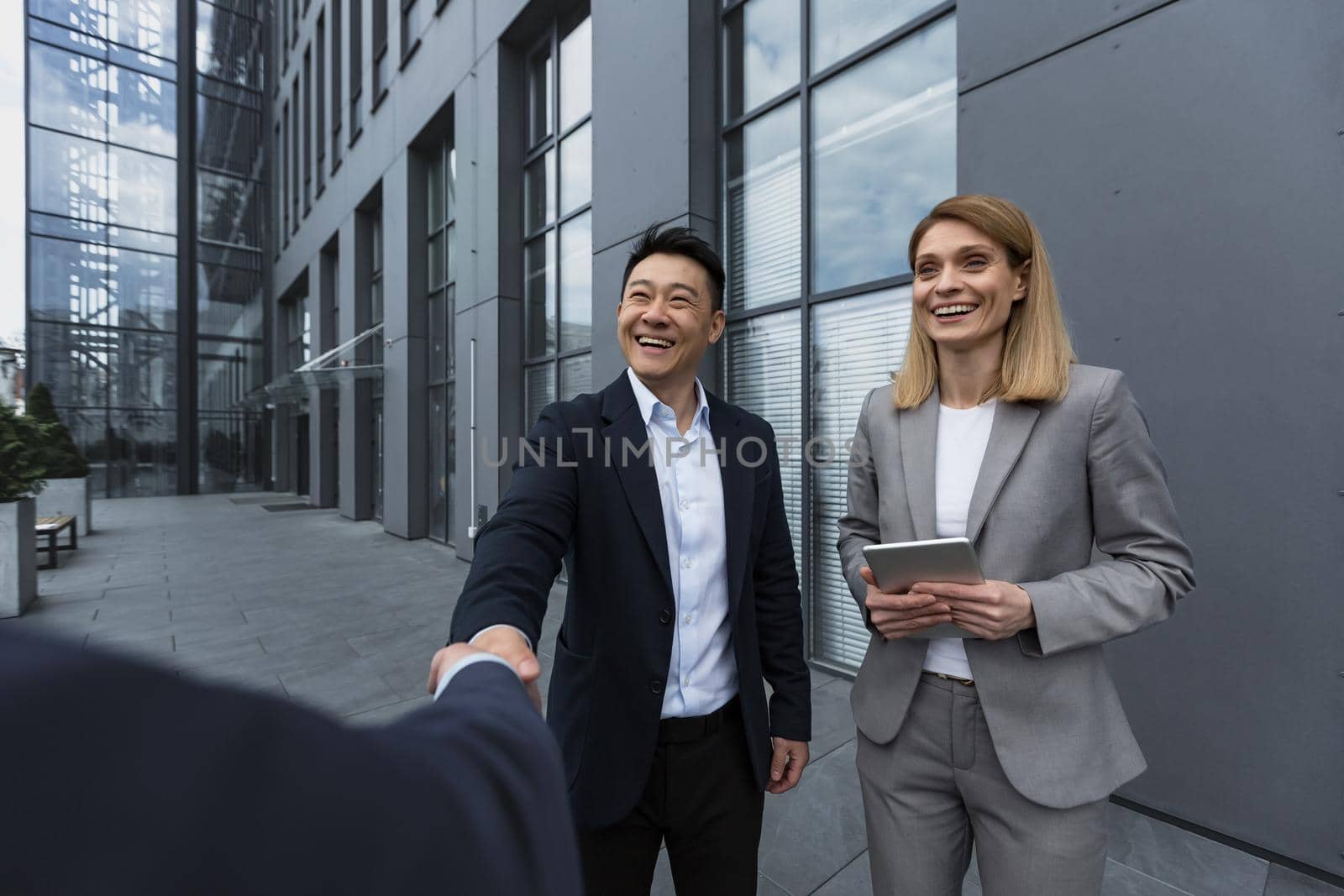 Three experienced managers team leaders, meet and get to know from outside the office team, diverse group of entrepreneurs shake hands men, introduce new colleague