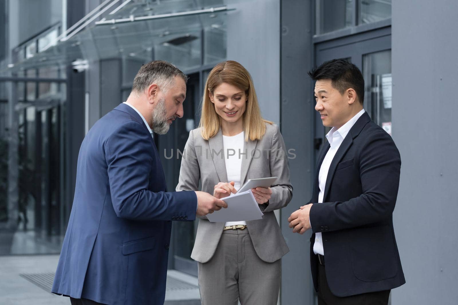 Happy and cheerful diverse business team of analysts engineers programmers discussing new app on tablet, group of business people having fun talking satisfied with work result.