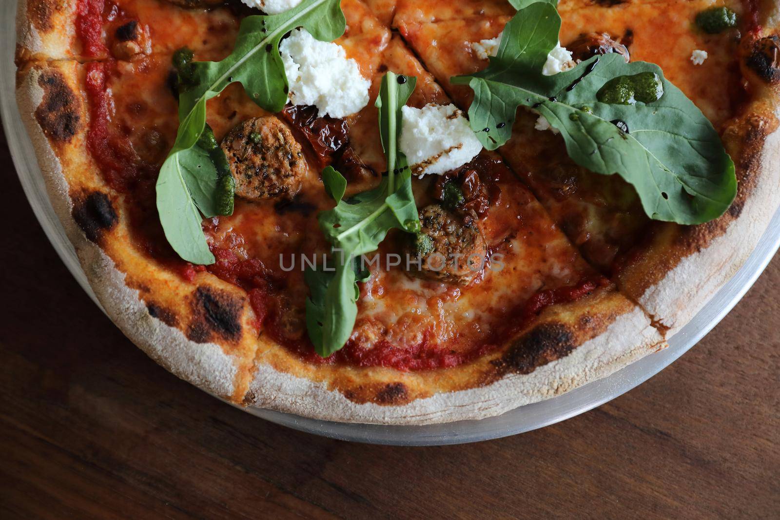 Italian Sausage and rocket salad pizza on wood background