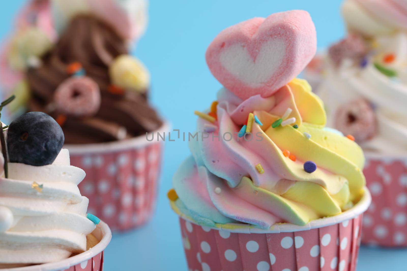 Colorful cupcakes isolated in blue background by piyato