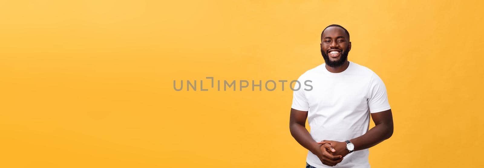 Portrait of delighted African American male with positive smile, white perfect teeth, looks happily at camera, being successful enterpreneur, wears white t shirt