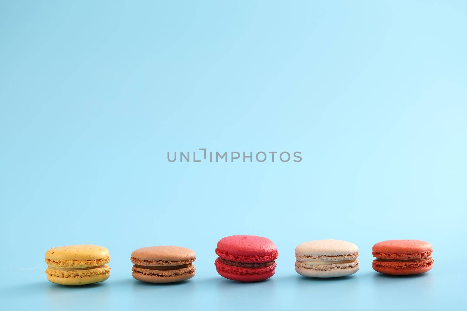 Colorful macarons isolated in blue background by piyato