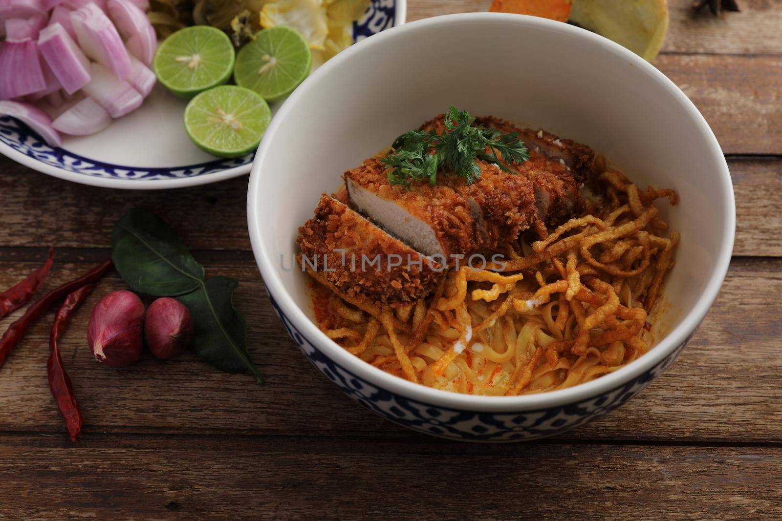 Local northern Thai food Egg noodle curry with fried pork on wood background by piyato