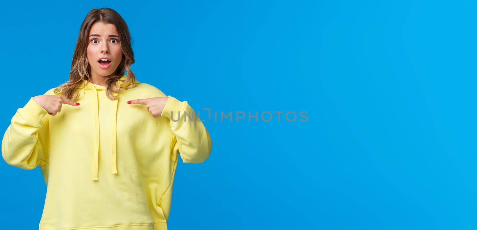 Surprised worried cute blond girl pointing at herself surprised with disbelief, cant understand if you really meant it, look camera nervously, being picked or chosen, stand blue background.
