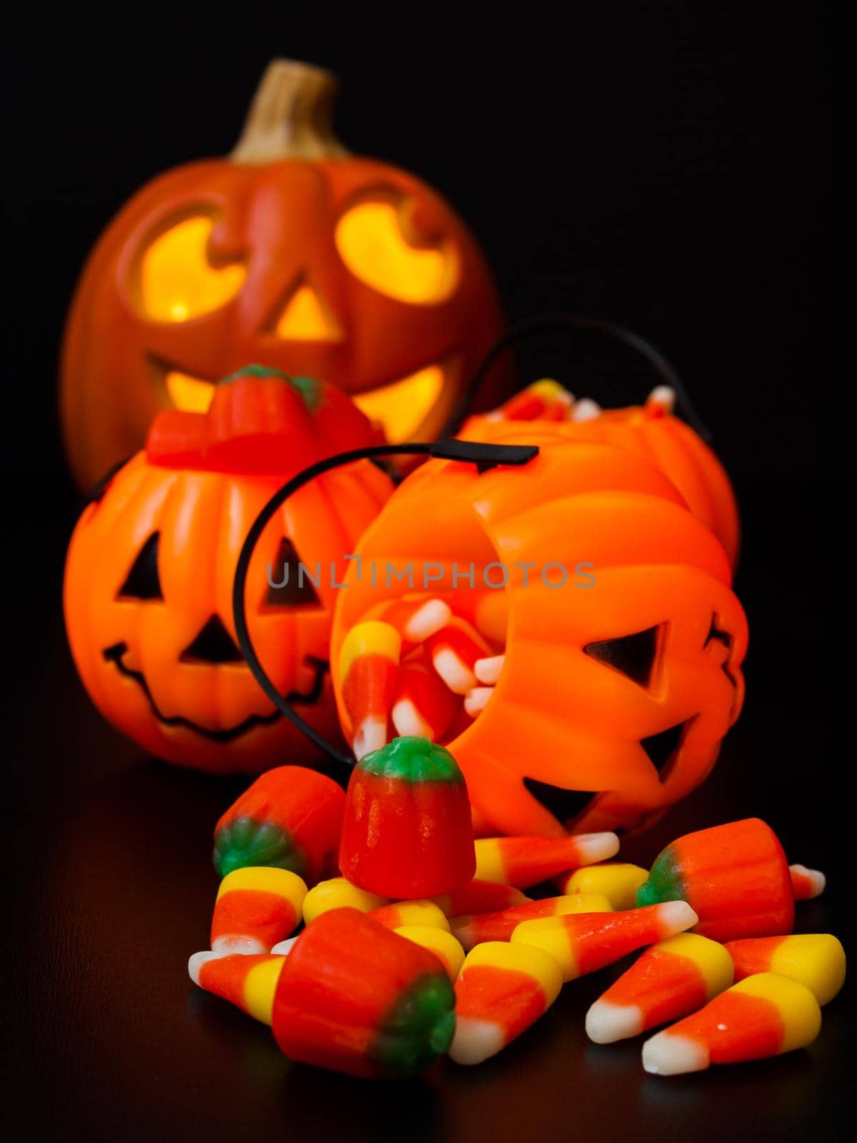 Lit jack-o'-lantern with Halloween pumpkin bags on black background.