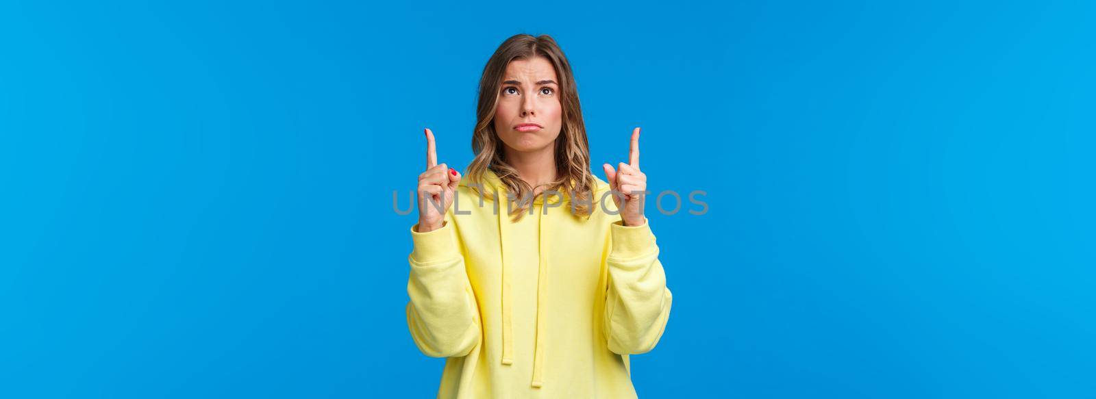 Jealous and gloomy cute blond female student feel regret not having something she desires, sobbing frowning sad as looking pointing up, standing over blue background by Benzoix