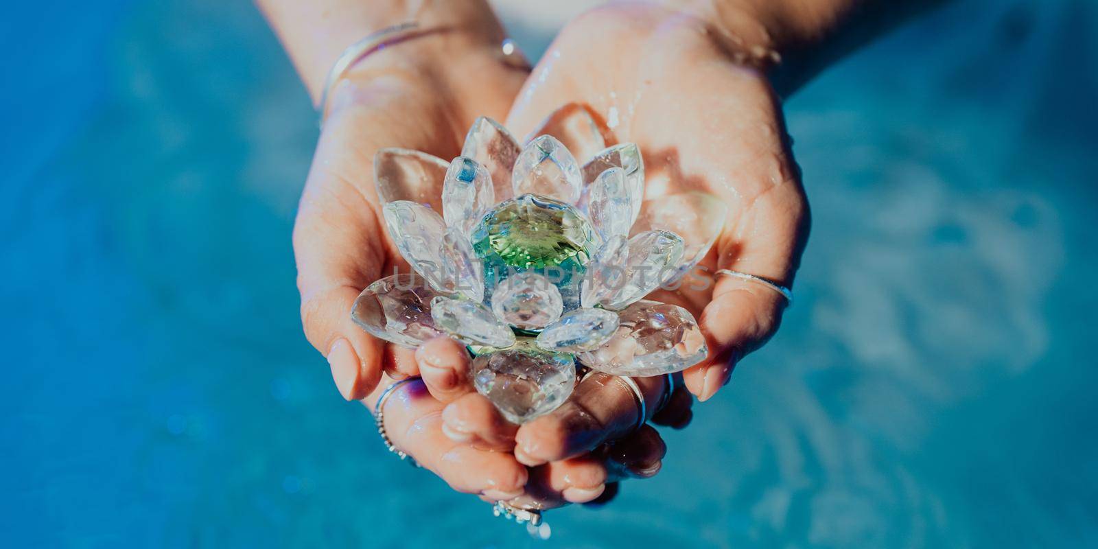 Woman holding fragile lotus flower. Clean water drops are dripping from crystal. Concept of religion, kundalini, meditation, chakras, spiritual inner world. High quality photo