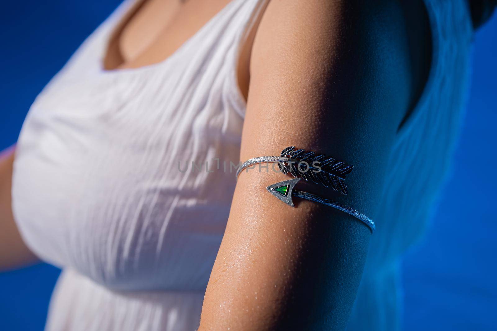 Woman with forearm bracelet in blue water, pool at night. Beautiful jewelry accessories, gypsy style. High quality photo