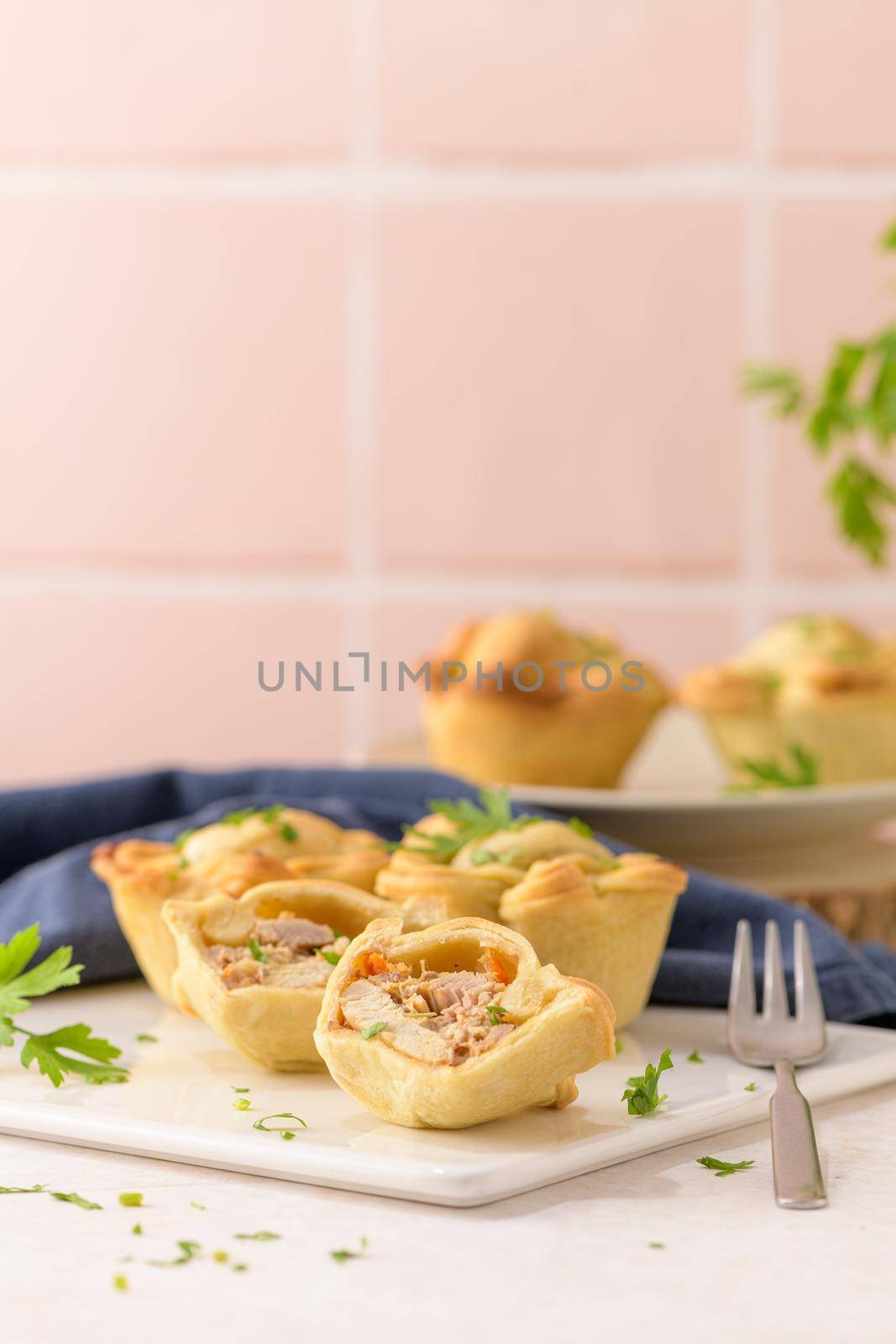 Chicken pies and parsley leaves on white ceramic dishes in a kitchen counter top.