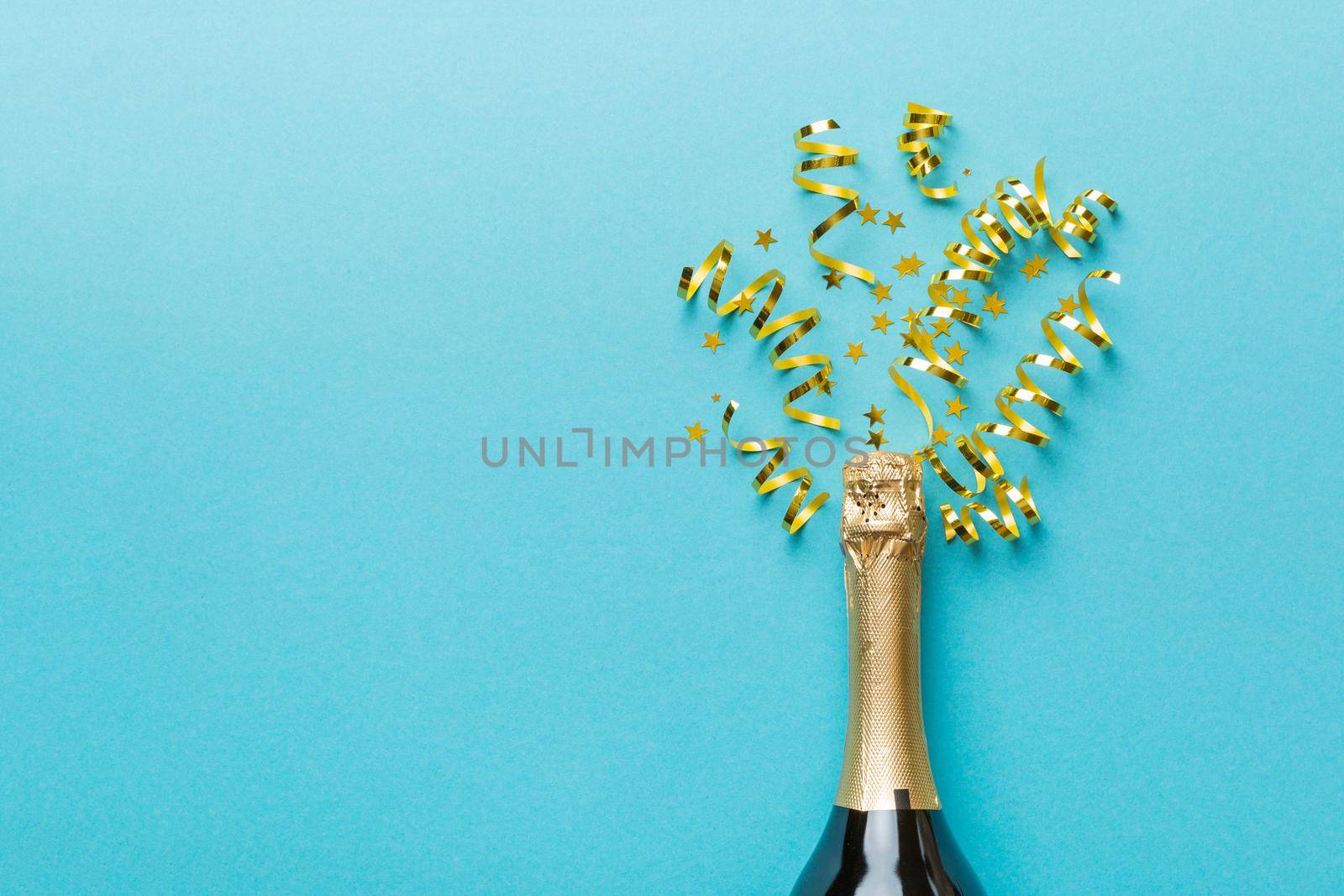 Creative flat lay composition with bottle of champagne and space for text on color background. Champagne bottle with colorful party streamers. holiday or christmas concept.