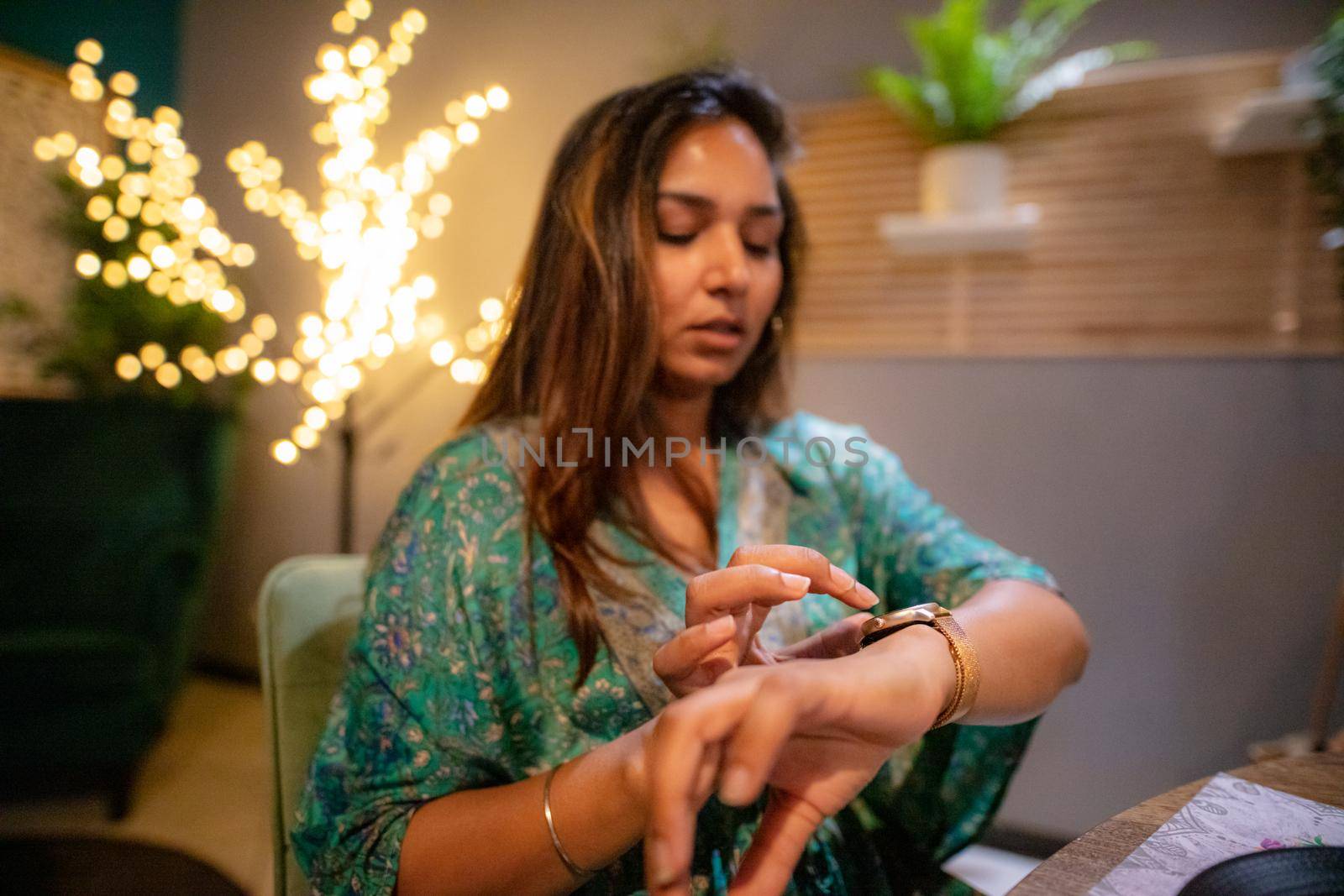 indian woman at the restaurant using smartwatch