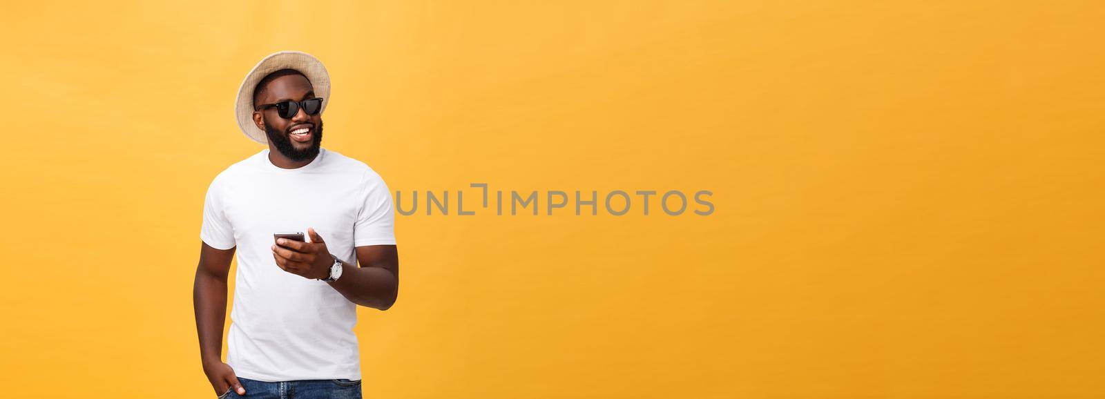 Cheerful African American man in white shirt using mobile phone application. happy dark skinned hipster guy read news from social network in mobile phone. by Benzoix