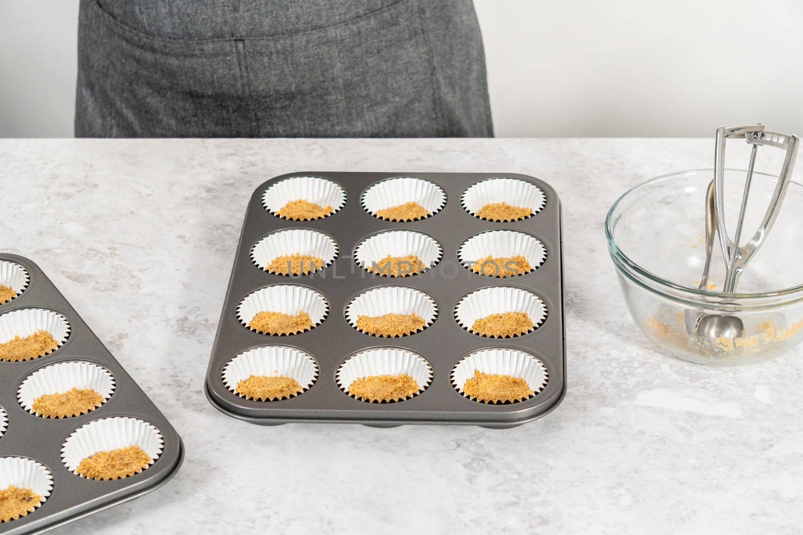 Filling cupcake liners with graham crackers to baking s'mores cupcakes.