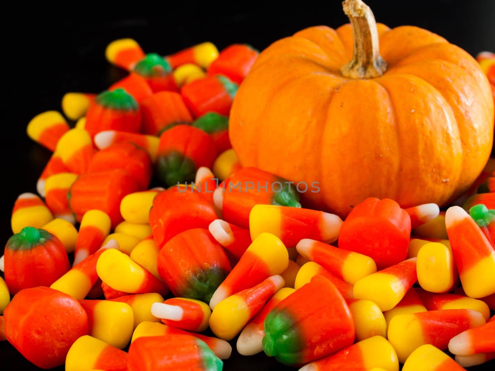 Halloween candy corn and pumpkin candies on black background.