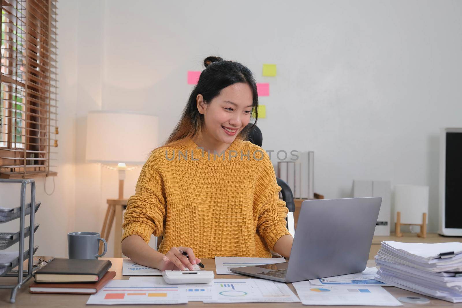 Business woman hand using calculator to calculate the company's financial results and budget. Account Audit Concept by wichayada