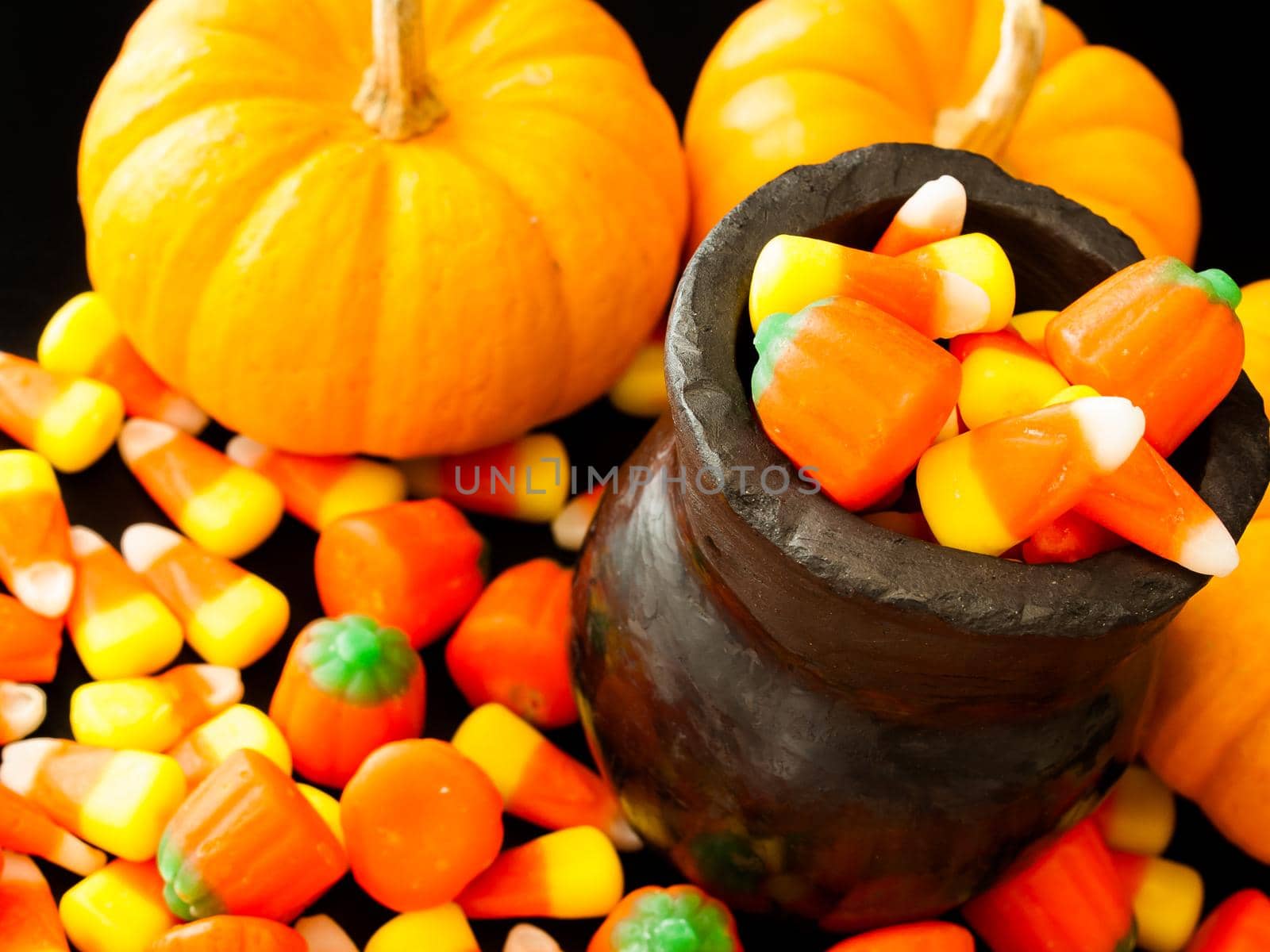 Halloween candies spilled on black background.