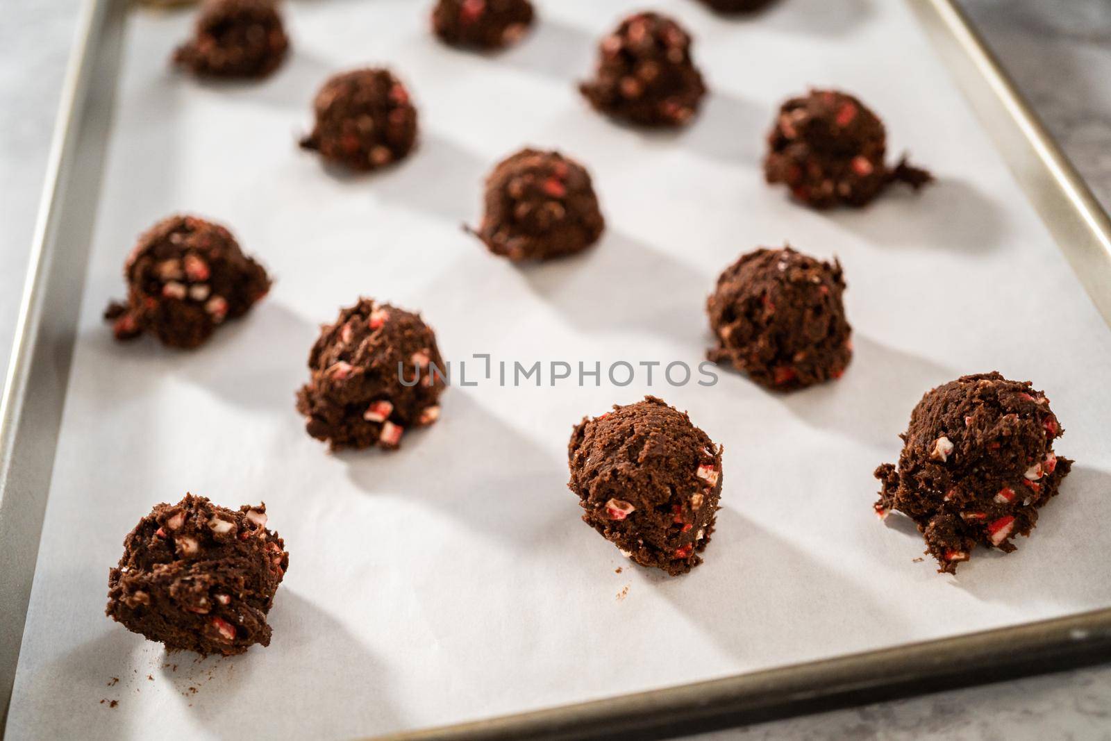 Scooping chocolate cookie dough with dough scoop to bake chocolate cookies with peppermint chips.