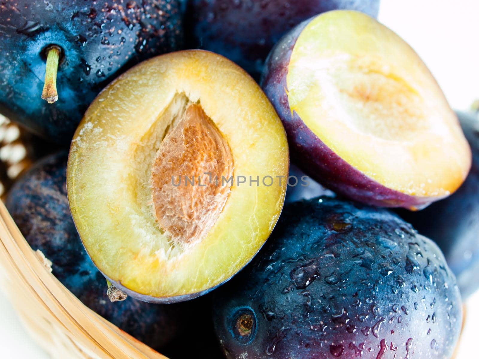 Fresh plums in basket on white background.