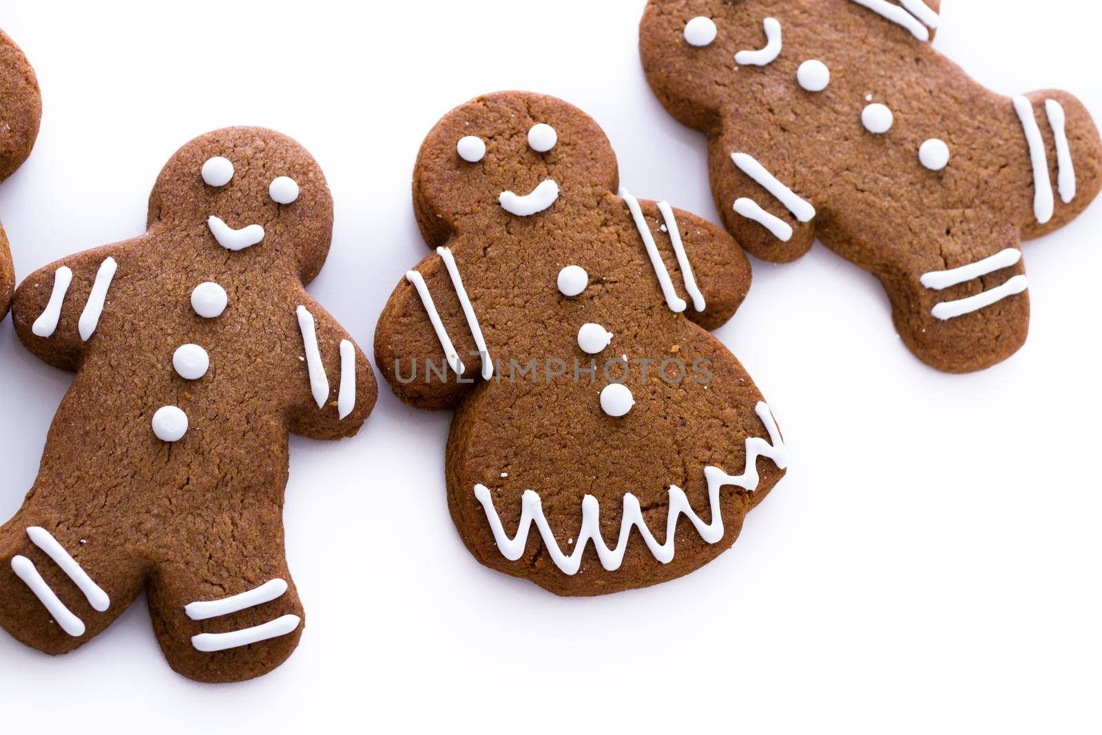 Homemade gingerbread cookies decorated with white icing on white background.