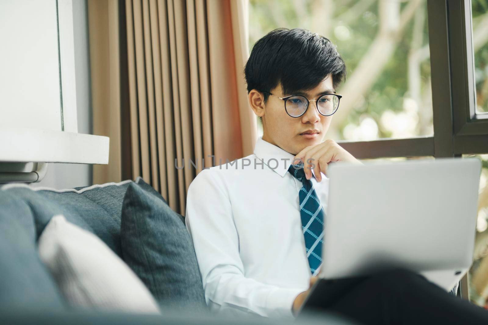 Young asian businessman working hard at the office using laptop data graphs, planning for improvement, snalyzing and strategizing for business growth. Business concept.