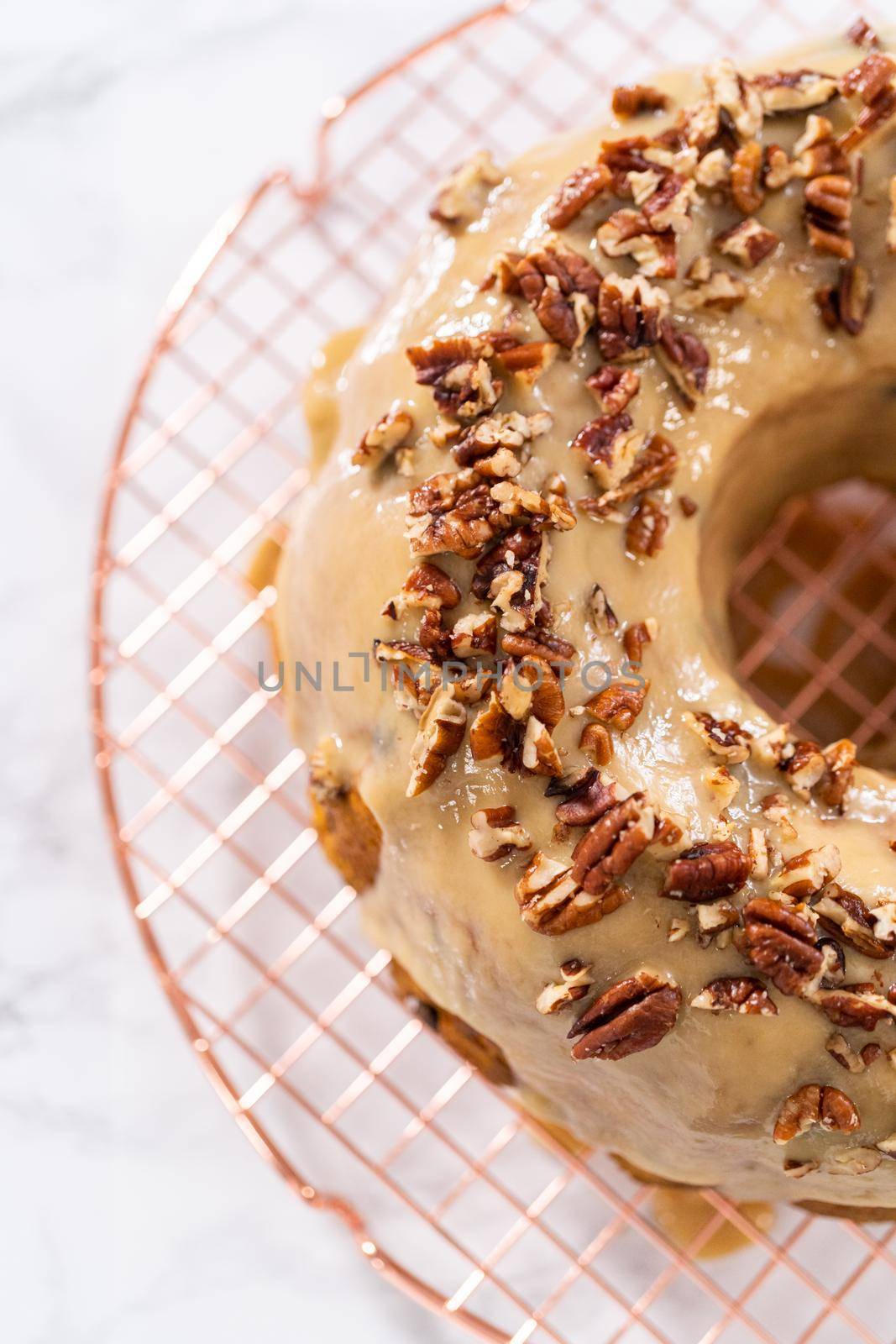 Frosting pumpkin bundt cake with a toffee glaze and garnish with toasted pecans.