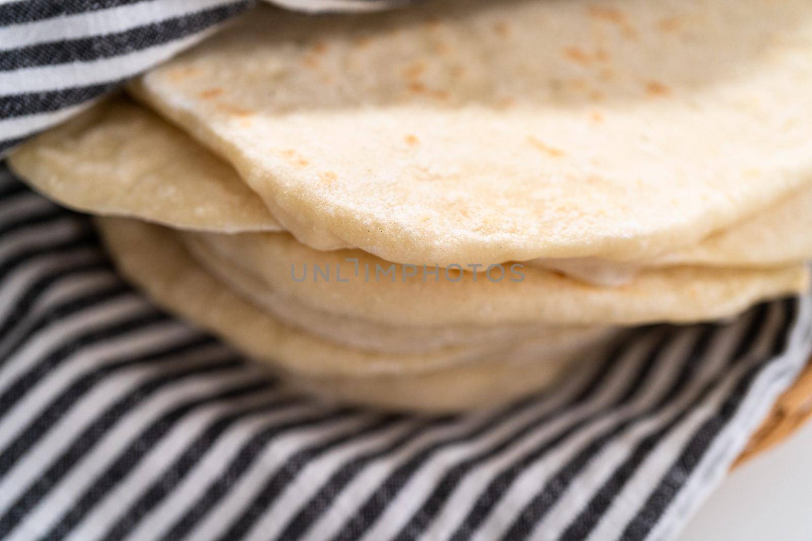 Stack of freshly baked flatbread wrapped in a kitchen towel.