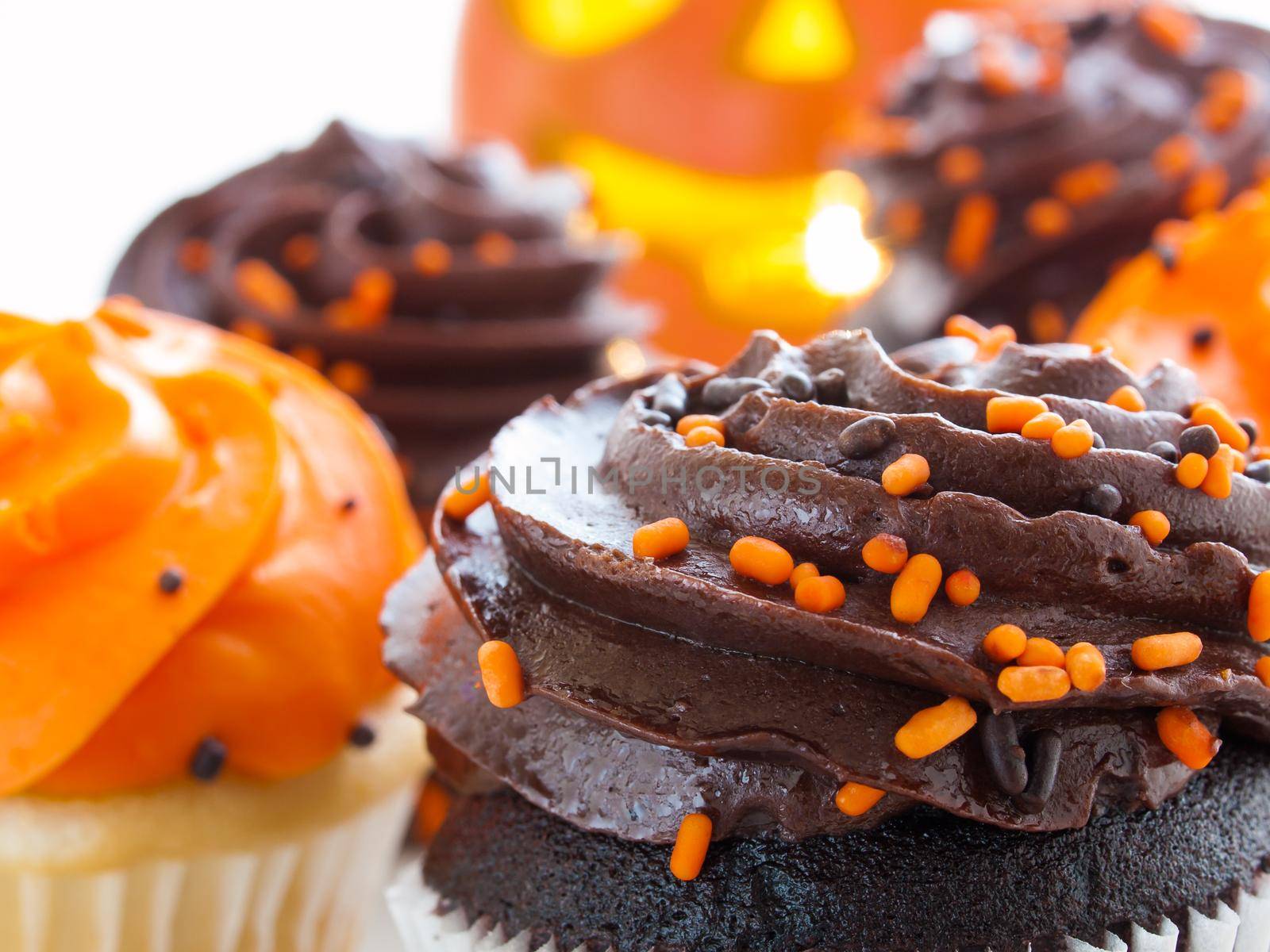 Halloween cupcakes with orange and black icing on white plate.