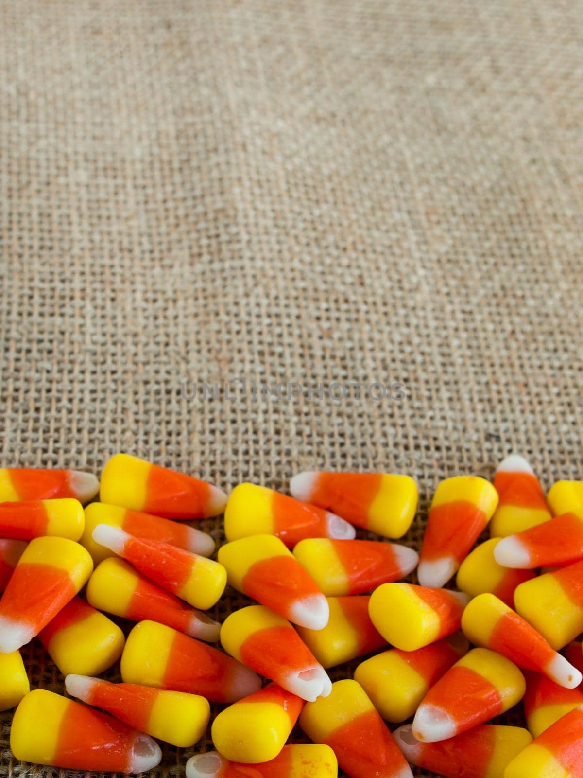 Traditional Halloween candies candy corn on burlap fabric.