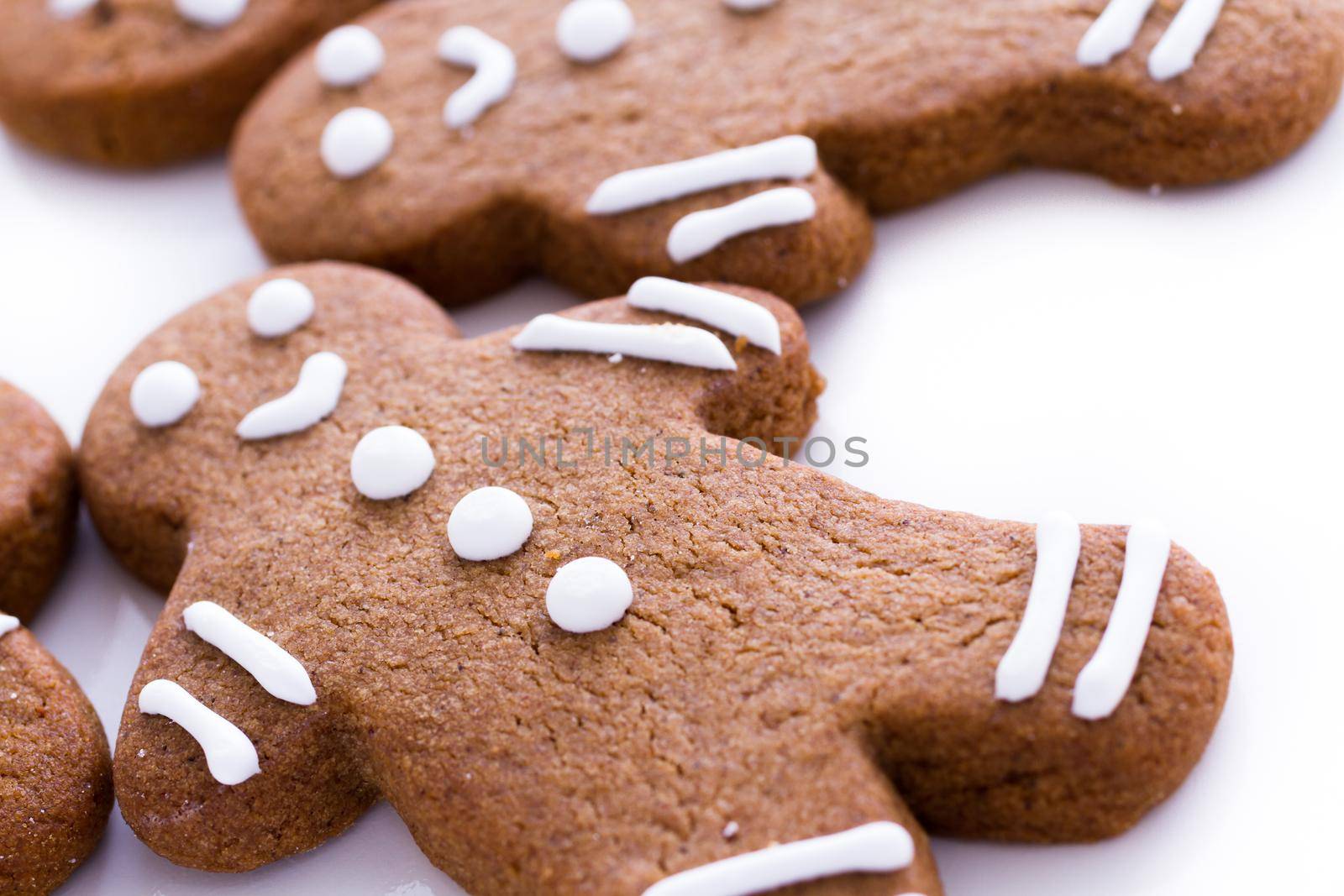 Homemade gingerbread cookies decorated with white icing on white background.