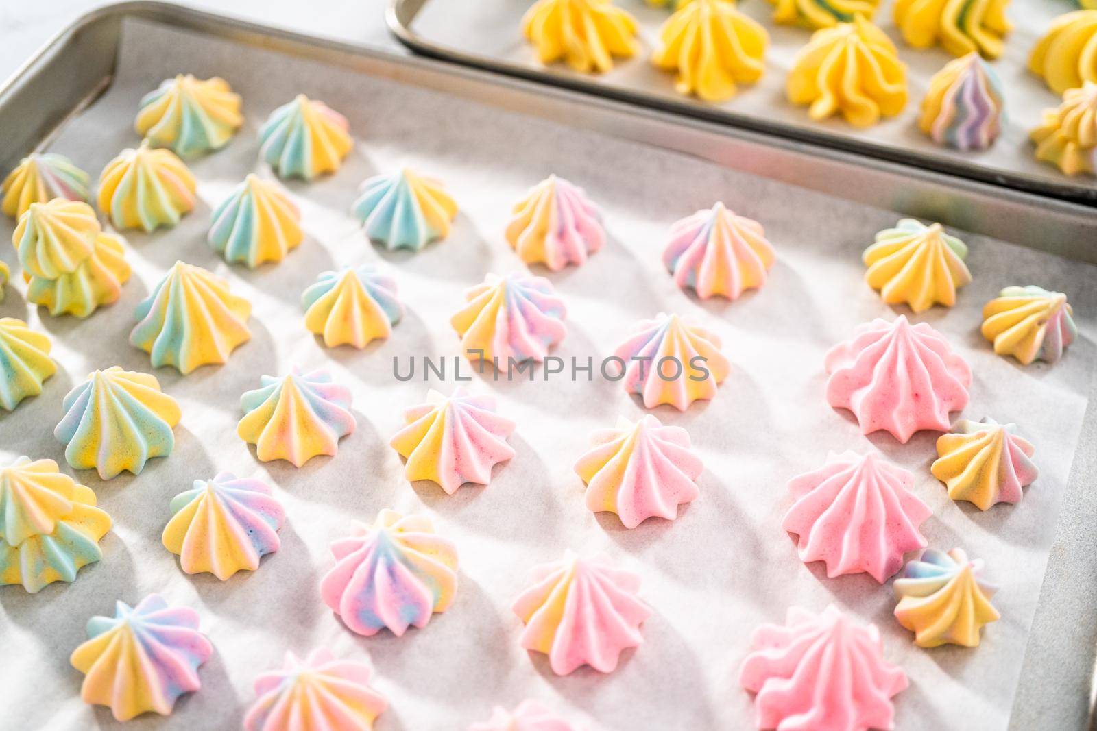 Freshly baked unicorn meringue cookies on a baking sheet with a parchment paper.