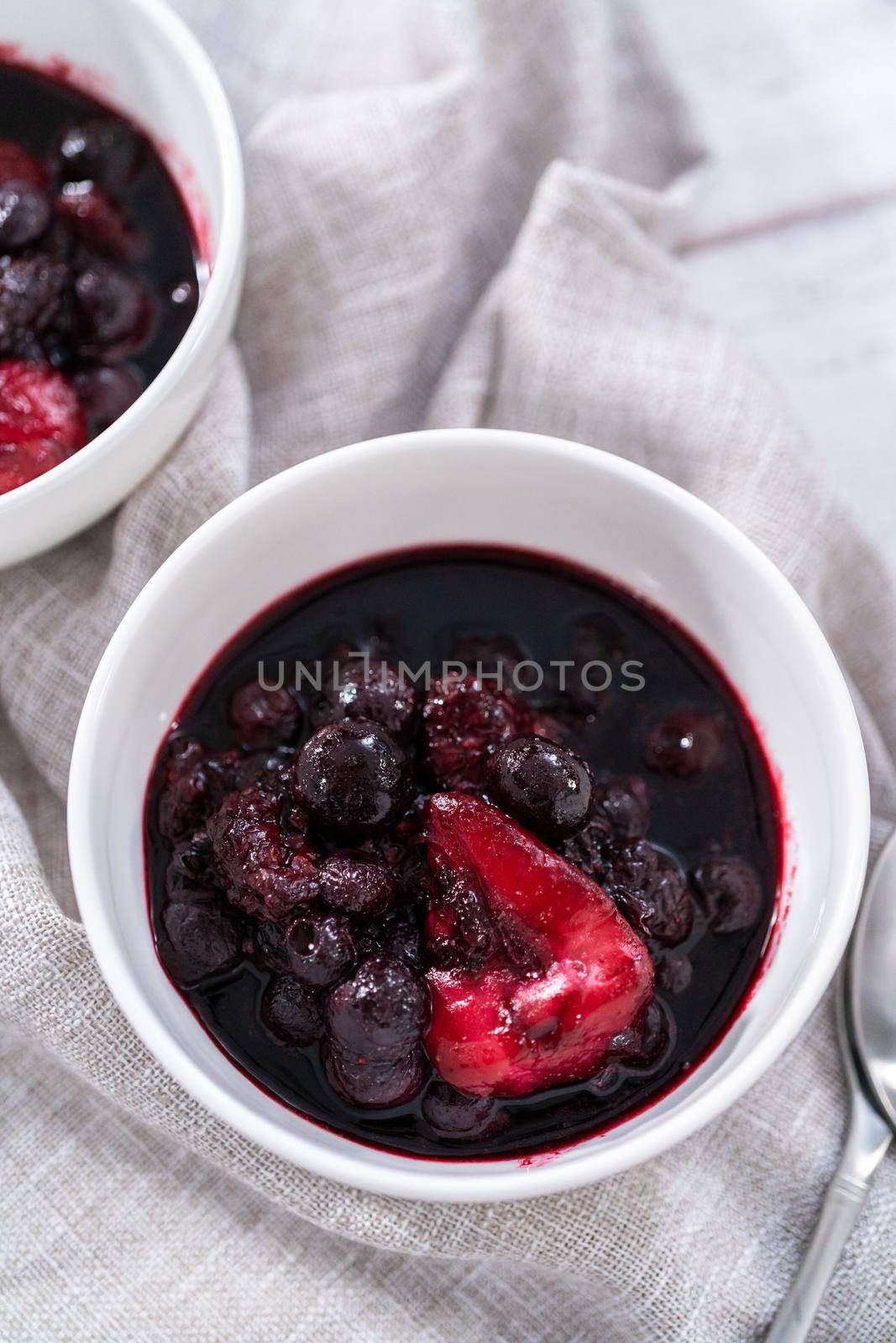 Homemade mix berry compote in small white bowls on a wooden table.