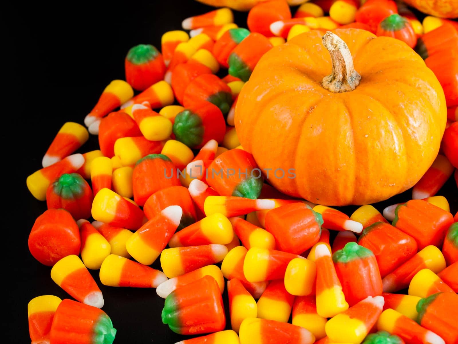 Halloween candy corn and pumpkin candies on black background.