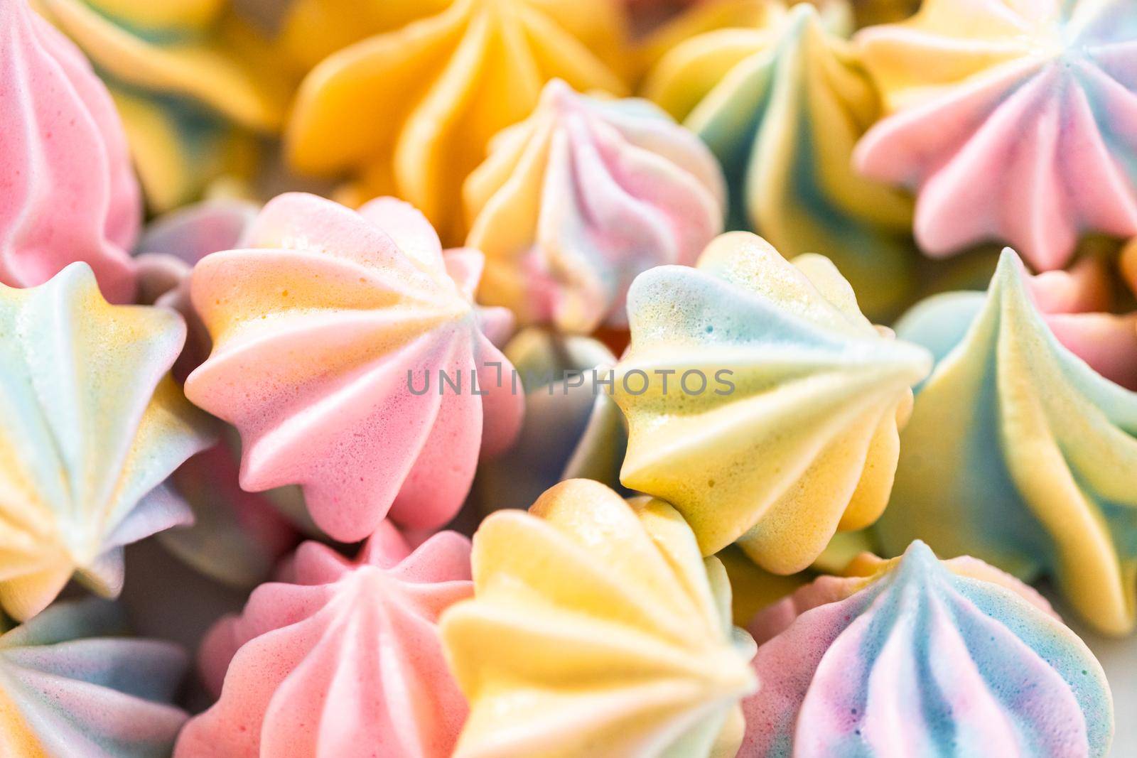 Multicolored unicorn meringue cookies on a white serving plate.