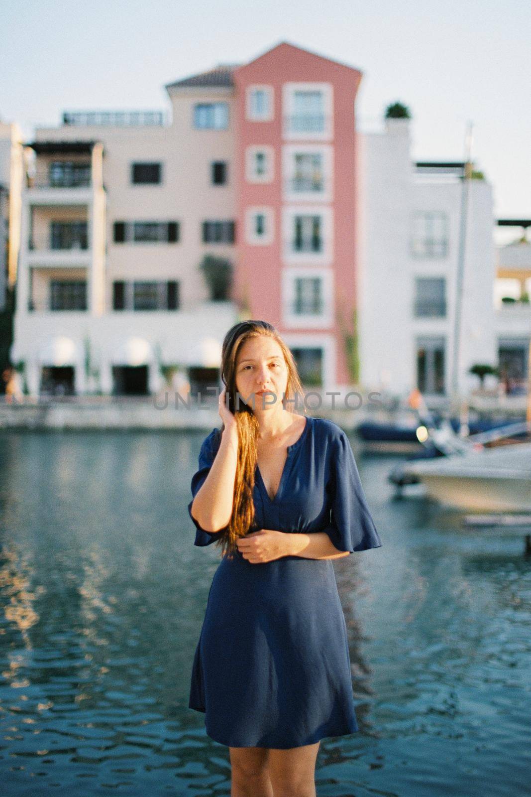 Young woman stands on the pier against the background of a multi-colored building. High quality photo