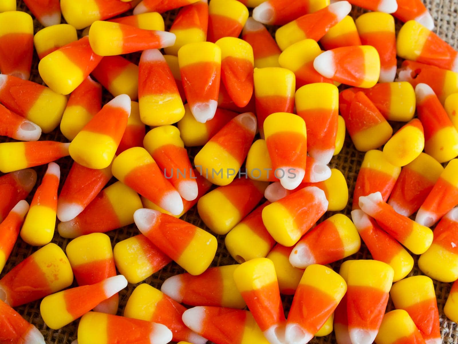 Traditional Halloween candies candy corn on burlap fabric.