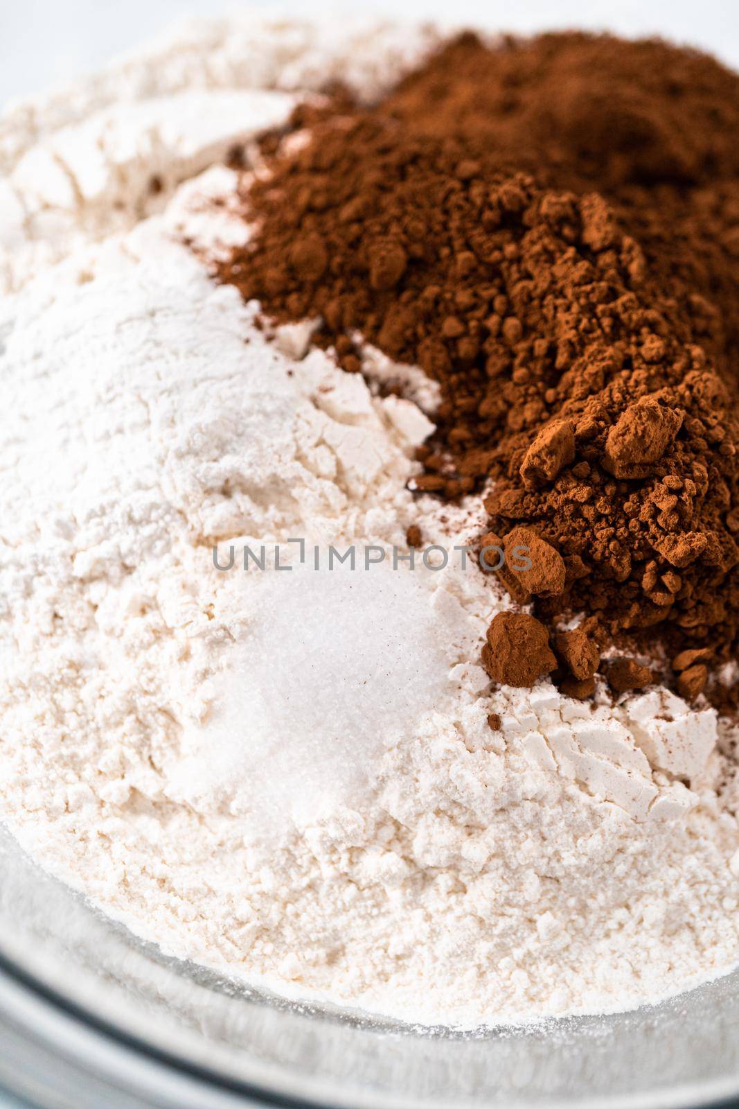 Mixing ingredients in a large glass mixing bowl to bake red velvet bundt cake with cream cheese glaze.