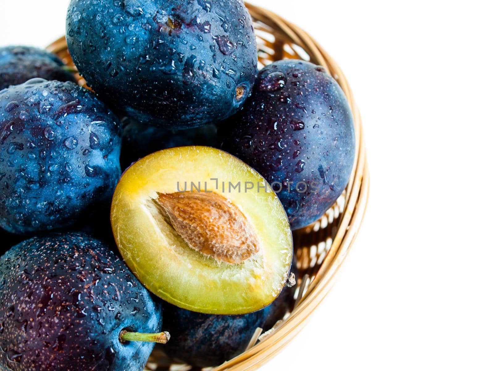 Fresh plums in basket on white background.