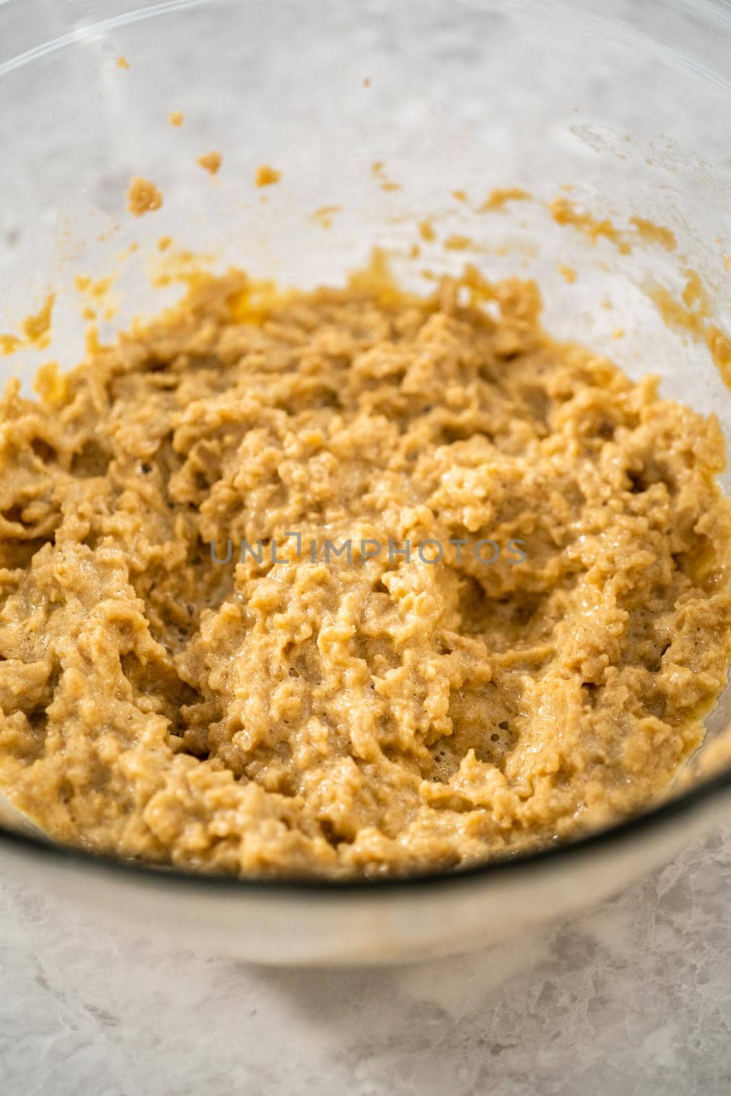 Mixing ingredients in a large glass mixing bowl with a kitchen mixer to bake chocolate cookies with peppermint chips.