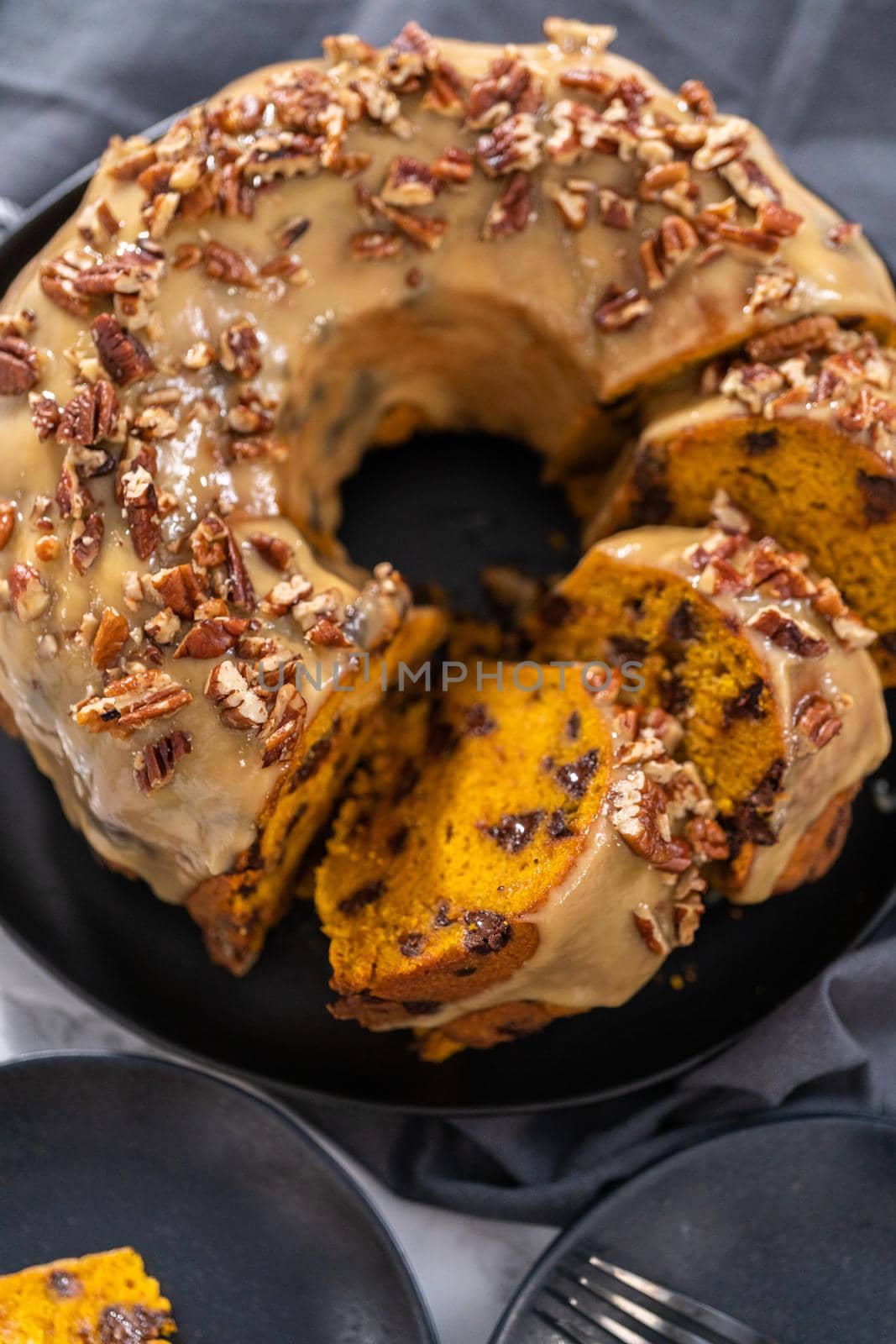Slicing homemade chocolate pumpkin bundt cake with toffee glaze.