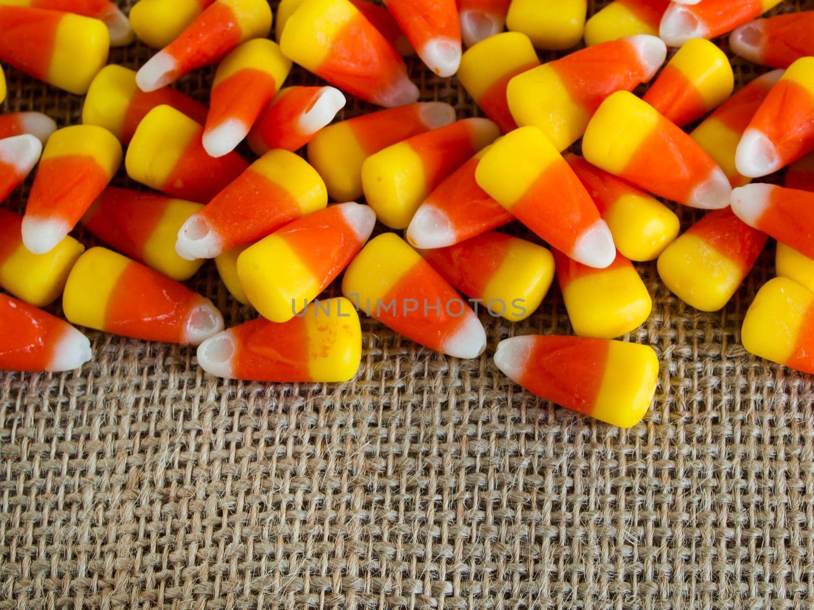 Traditional Halloween candies candy corn on burlap fabric.